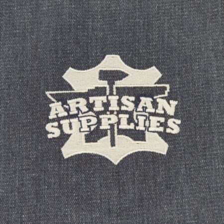 Close up of the white logo embroidered on the front of the Artisan Supplies Denim Apron